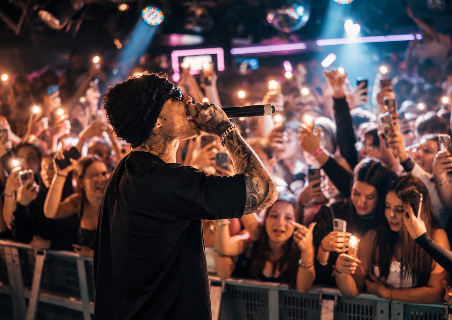 Artista sul palco davanti al pubblico con i telefoni accesi